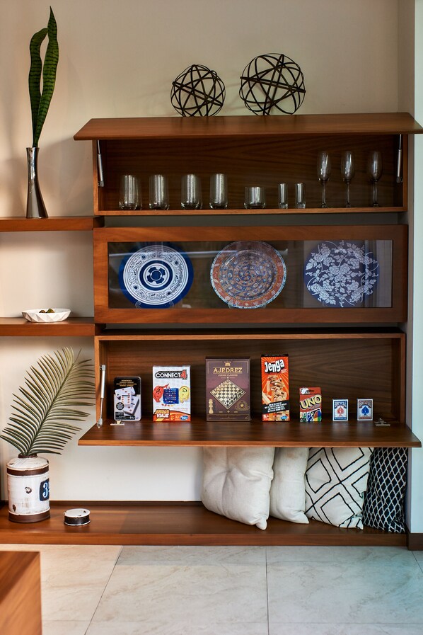 A wooden shelf with decorative plates, a plant, and board games.
