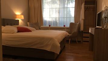 Une chambre d’hôtel avec un grand lit, un bureau, une chaise, une télévision et une armoire.
