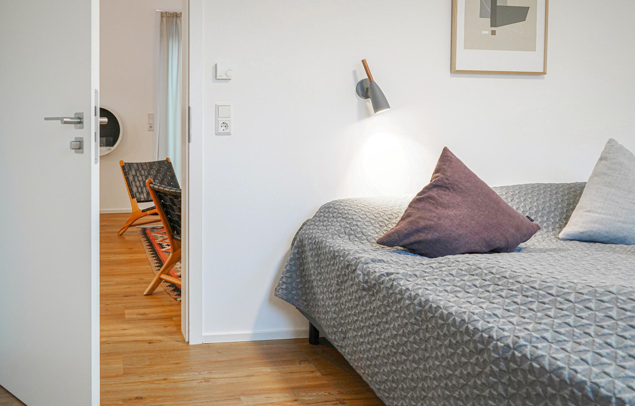 Une chambre à coucher avec un lit, une chaise et un luminaire fixé au mur.