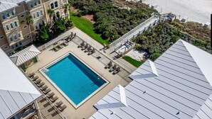 Un resort con piscina, acceso a la playa y un edificio de varios pisos con balcones.
