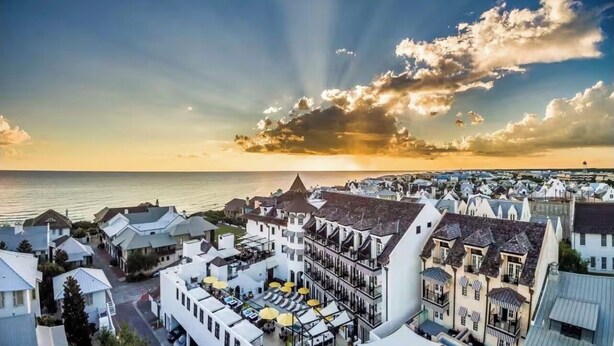 Un pueblo costero con edificios blancos, una estructura triangular destacada y vista al mar.