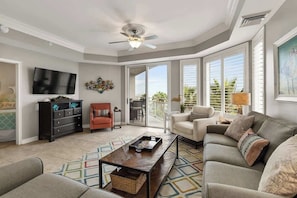 A living room with a television, sofa, coffee table, and a balcony with outdoor furniture.