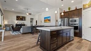 Una cucina moderna con mobili in legno scuro, elettrodomestici in acciaio inossidabile e luci a sospensione.