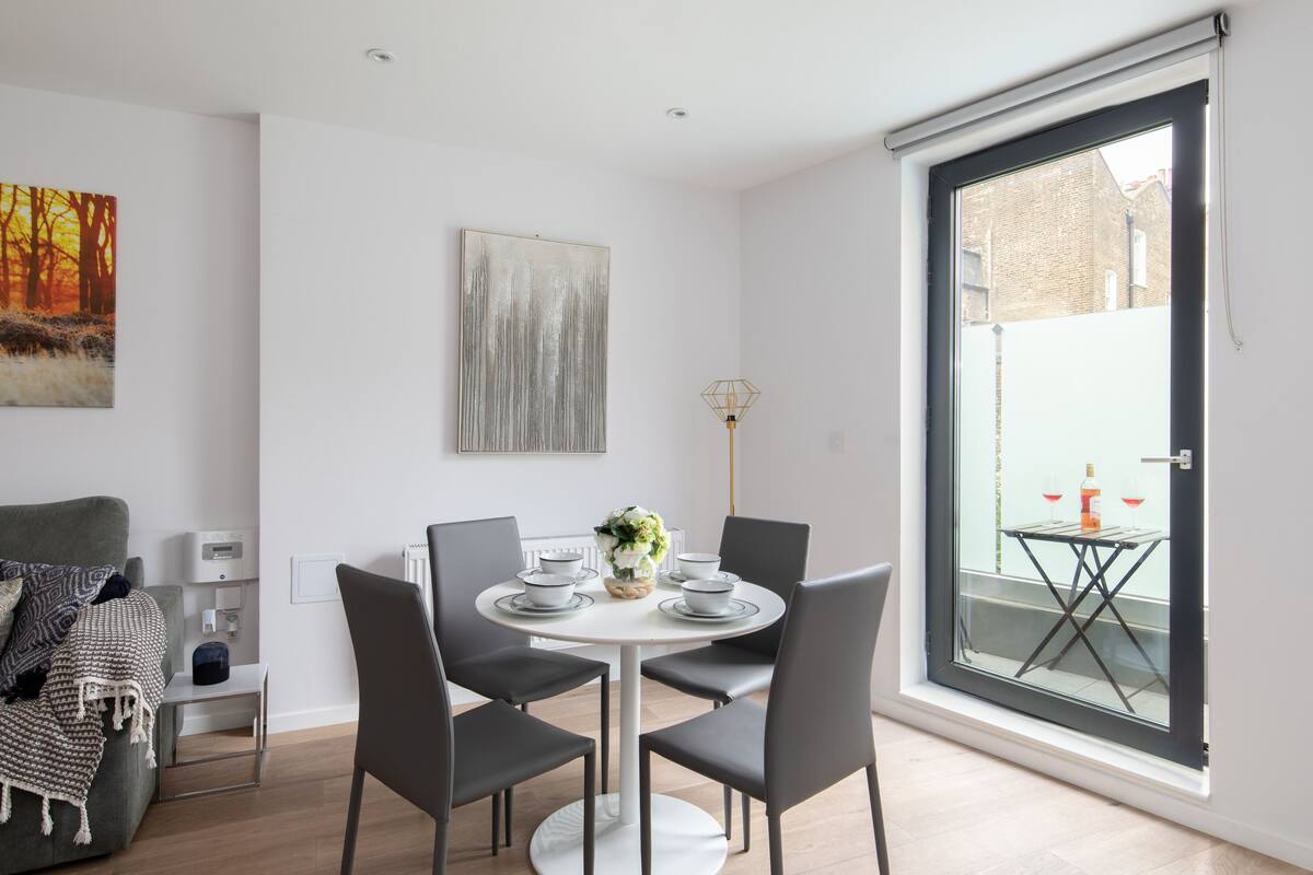 A modern dining area with a round table, four chairs, and a vase of flowers.