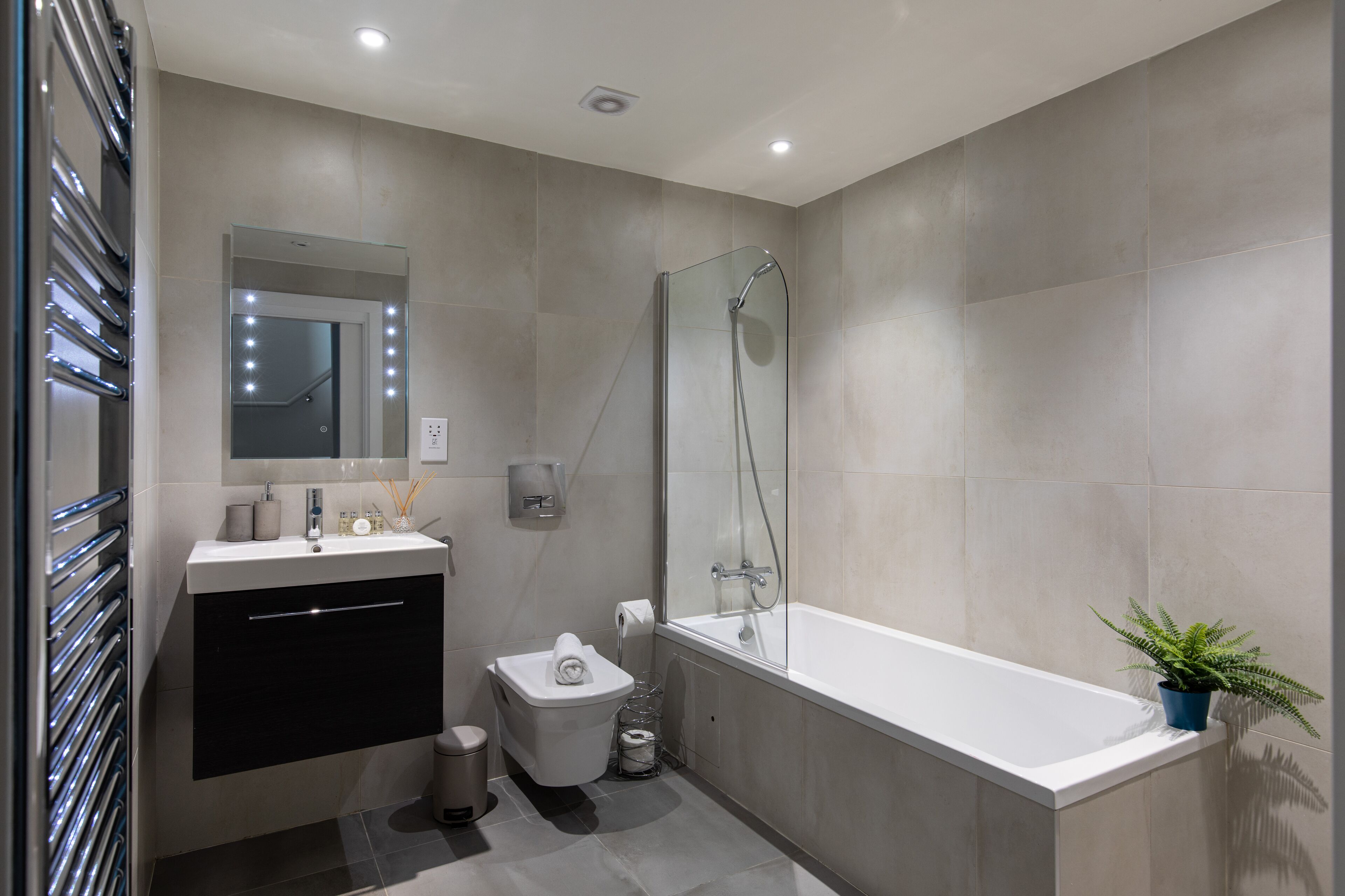 A modern bathroom with a glass-enclosed shower, a white bathtub, and a black vanity.