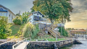 A waterfront property with a multi-level house, a dock, and a small bridge.