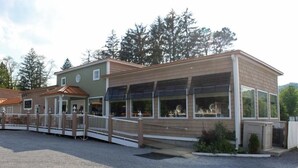 A two-story building with a covered outdoor area and a gravel driveway. - Lake Front Hotel (Cooperstown)