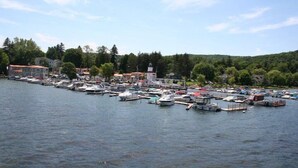 A marina with numerous boats docked, surrounded by buildings and trees. - Lake Front Hotel (Cooperstown)