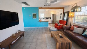 A modern living room with a TV, wooden bench, red sofa, and a coffee table. - South Congress Zen Den! Walk Everywhere! (Austin)