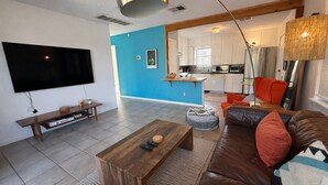 A modern living room with a large flat-screen TV, a wooden coffee table, a brown leather sofa, and a blue accent wall. - South Congress Zen Den! Walk Everywhere! (Austin)