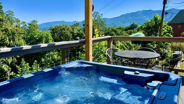 A hot tub on a wooden deck with a view of mountains.