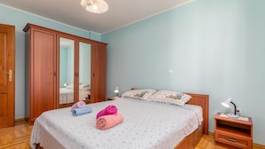 Un dormitorio con cama, mesita de noche, armario y lámpara en el techo.