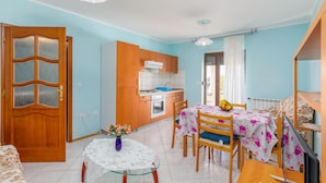 Un espacio habitable compacto con comedor, cocina y una puerta con paneles de vidrio esmerilado.