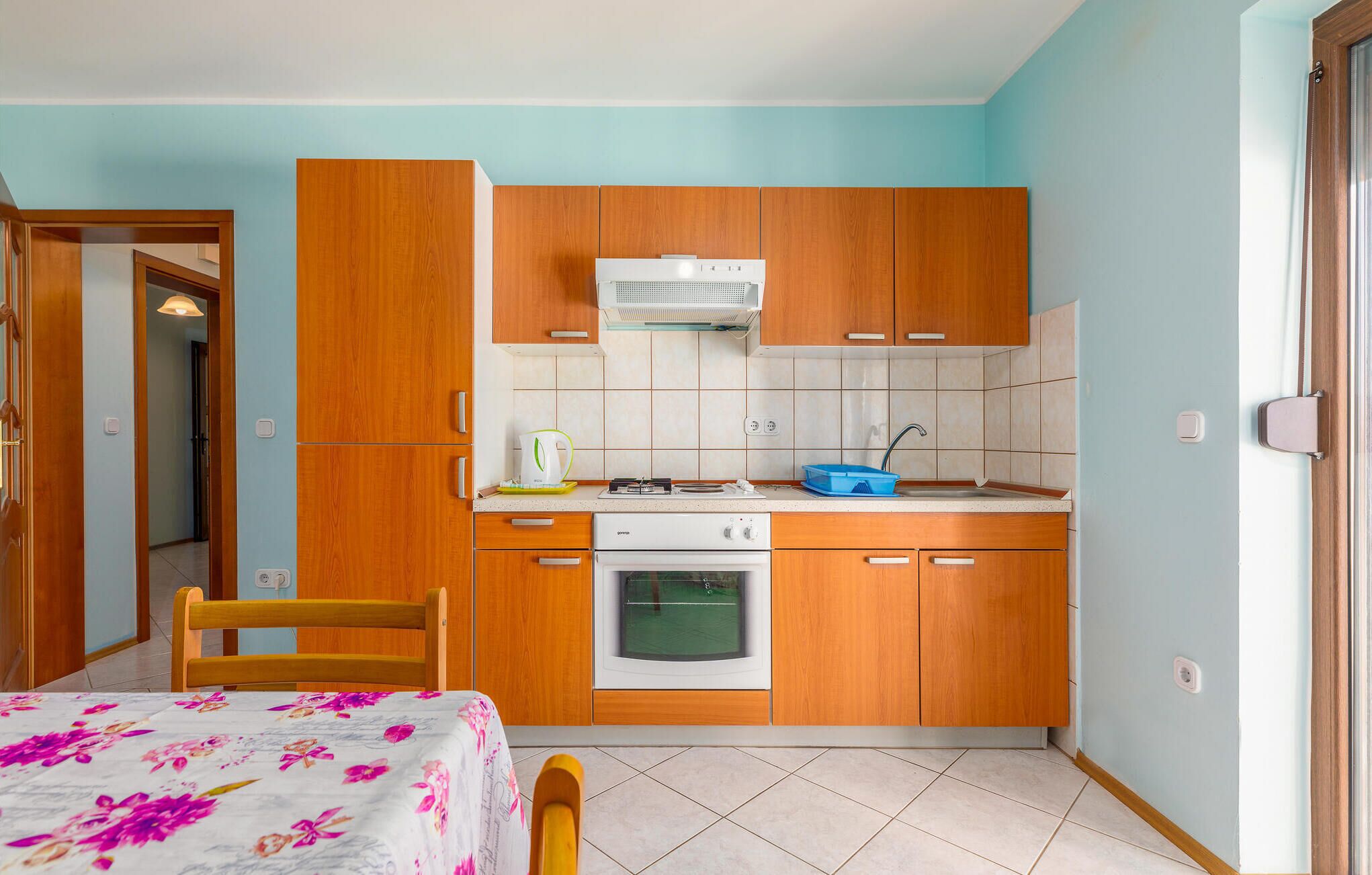 A compact kitchen with wooden cabinets, a built-in oven, and a sink.