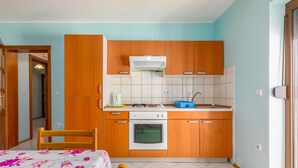 Una cocina compacta con armarios de madera, horno integrado y un lavamanos.