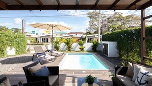 A covered outdoor area with a swimming pool, lounge chairs, and a sofa. - Modern Stylist 3 BR Beach House, w/Private Pool & Fast WiFi. (Jaco)