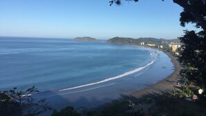 A coastal view with a beach, a small island, and buildings in the background. - Modern Stylist 3 BR Beach House, w/Private Pool & Fast WiFi. (Jaco)