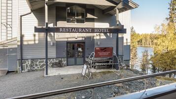 A restaurant hotel with a signboard, outdoor seating, and a view of a lake.