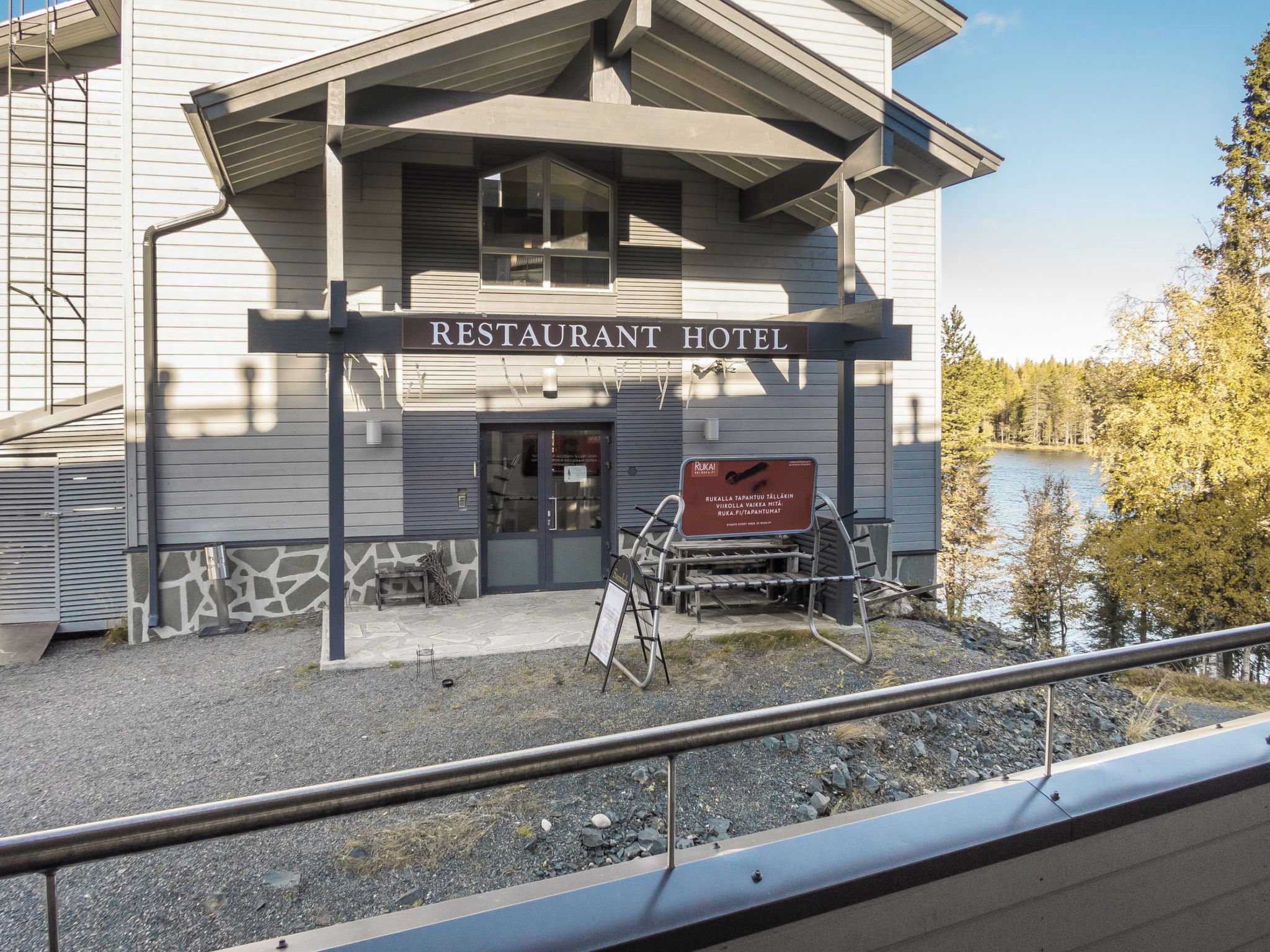 Un hôtel-restaurant doté d’une enseigne, de tables en plein air et offrant une vue sur un lac.
