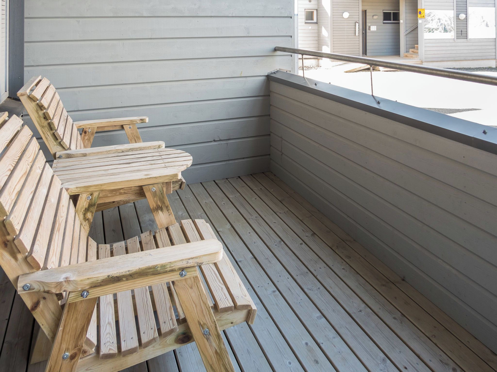 A wooden deck with benches and a railing.