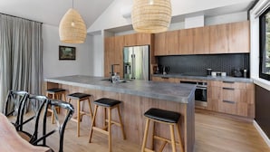 Een moderne keuken met houten kastjes, een groot eiland met barkrukken en hanglampen.