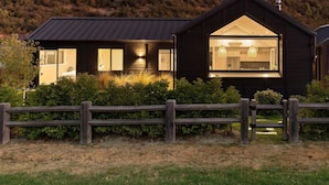 Een modern huis met een donkere gevel, grote ramen en een houten omheining.