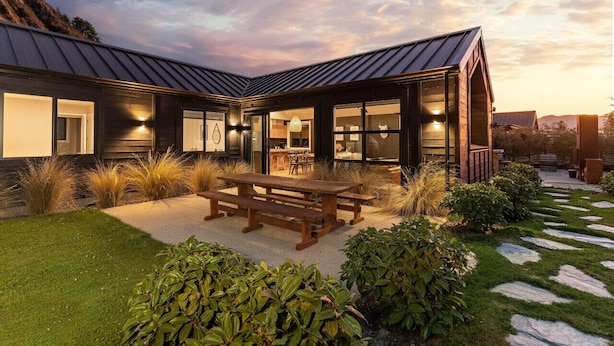 Een modern huis met een terras, buitenmeubels en uitzicht op het omliggende landschap.