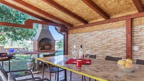 An outdoor patio with a brick wall, a wooden ceiling, and a pizza oven.