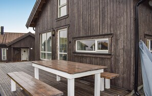 A wooden deck with a white table and benches.