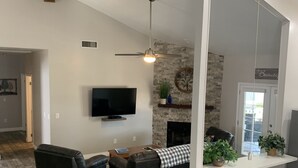 Un salon moderne avec une cheminée, un téléviseur et un mur d’accent en pierre.