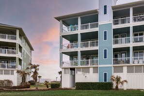 A multi-story residential building with balconies, a gated entrance, and a well-maintained lawn. - YOU, ME, BY THE SEA - Spacious Bay-View Retreat at Pointe West (Galveston)