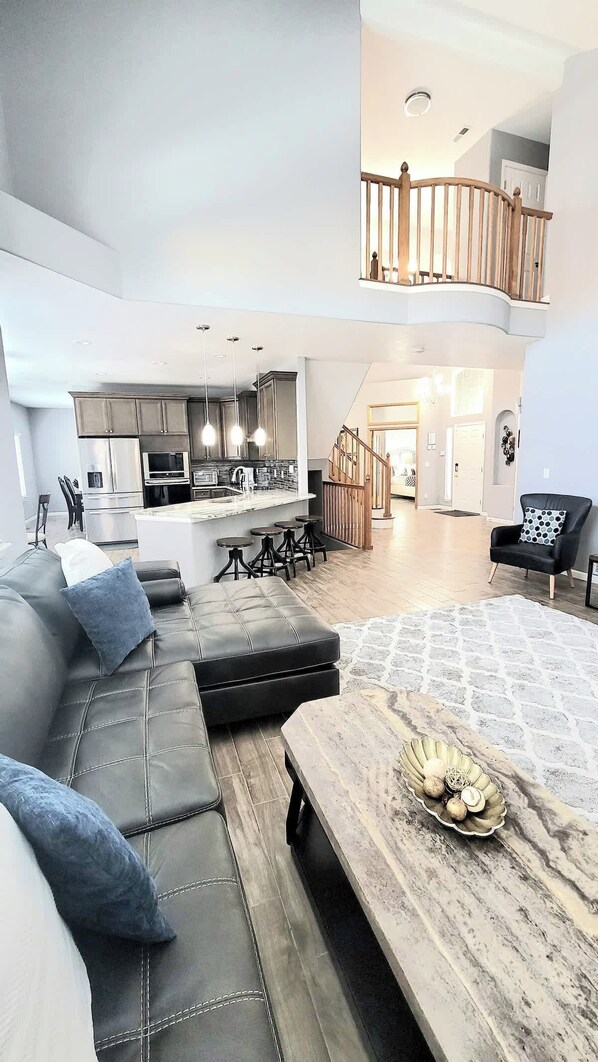 A modern living space with a sofa, a dining table, a kitchen, and a staircase.