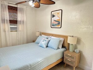 A neatly arranged bedroom with a bed, bedside lamps, a small nightstand, and a ceiling fan. - Sparkling Clean, Updated 2BR/1BA Beach Condo. Unbeatable Location. (Longboat Key)