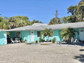 A two-story building with a turquoise exterior and a gravel driveway. - Sparkling Clean, Updated 2BR/1BA Beach Condo. Unbeatable Location. (Longboat Key)