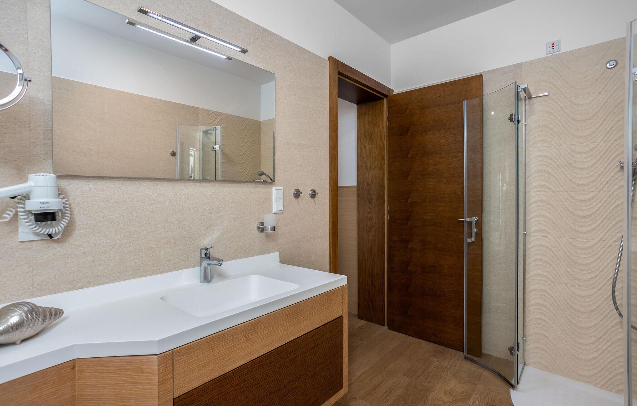 Uma casa de banho moderna com uma grande pia, um espelho e cabine de duche em vidro.