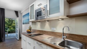 Una cocina moderna con microondas integrado, pileta de acero inoxidable y encimera de madera.