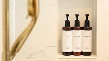 Un estante de baño con tres botellas de champú y acondicionador del hotel Fauchon.