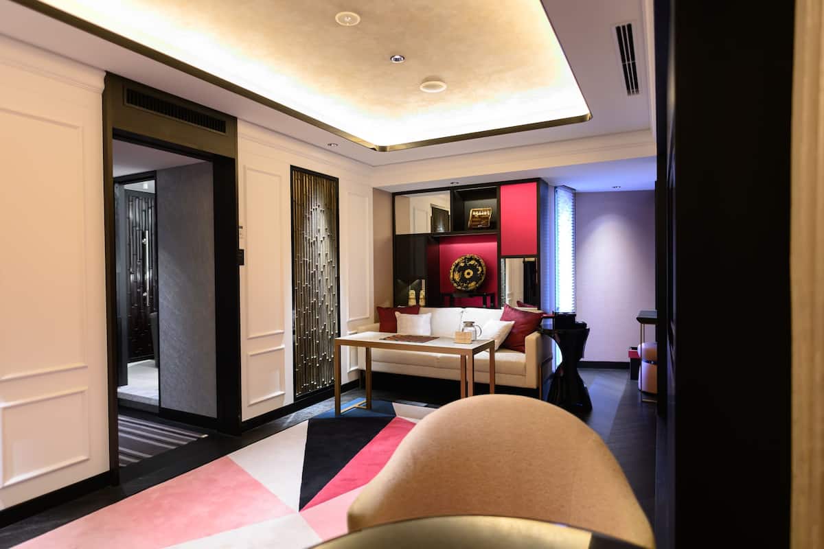 A modern hotel room with a sofa, a coffee table, and a decorative mirror.