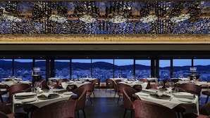 A restaurant with tables set for dining, large windows offering a city view, and a decorative ceiling. - Fauchon Hotel Kyoto (Kyoto)