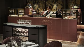 A bar area with a bartender, a well-lit bar counter, and a dining setup with tables and chairs.