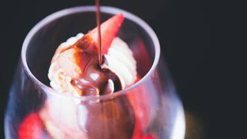 Postre en vaso con una bola de helado y salsa de chocolate vertida encima.
