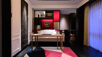 A modern hotel room with a sofa, a small table, and a decorative wall piece.