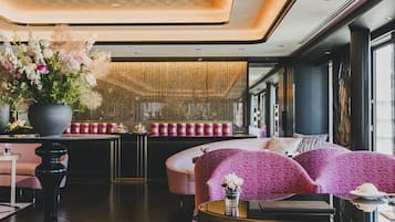 A modern interior with a seating area, a large vase of flowers, and a table with a cup and saucer.