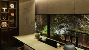 A modern bar area with a long counter, stools, and a view of a garden through large windows. - Fauchon Hotel Kyoto (Kyoto)