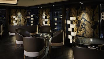 A modern interior with leather chairs, a glass table, and wall-mounted lamps.