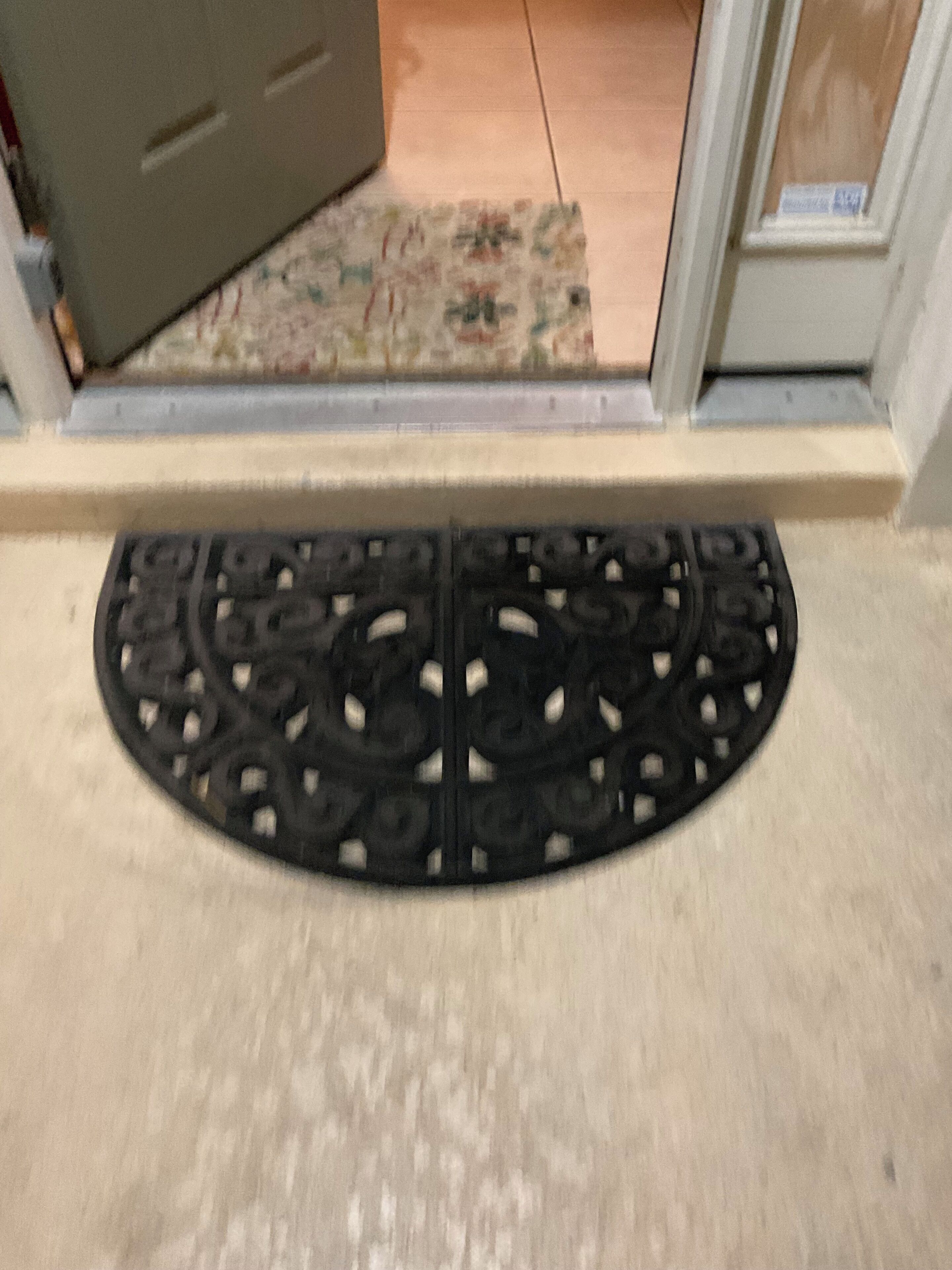 A black, ornate doormat with a circular design.