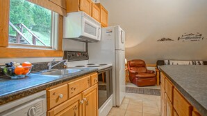 A kitchen with wooden cabinets, a built-in microwave, a refrigerator, a stove, and a sink.