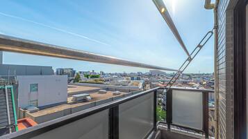 A rooftop terrace with a view of the cityscape, including buildings and a clear sky.