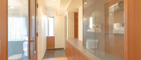 A hallway with wooden cabinets, a glass shower enclosure, and a tiled floor.