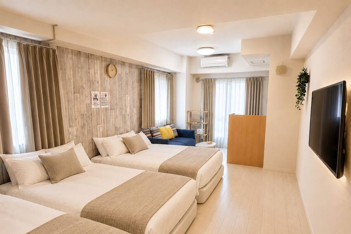 A hotel room with three beds, a TV, and a wooden wall.